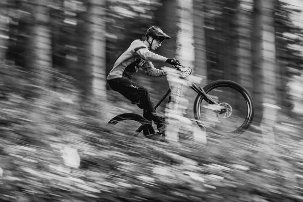 Vététiste roulant à grande vitesse sur un sentier forestier, illustrant le contrôle et la performance